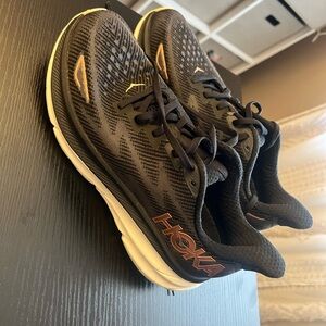 Gently used Hoka Sneaker with bronze Hola symbol